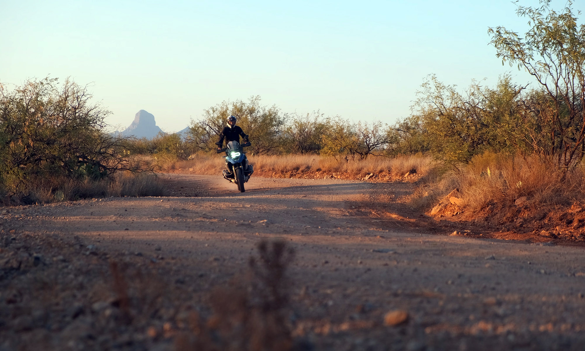 Sterling Noren riding BMW motorcycle Baboquivari Peak in background