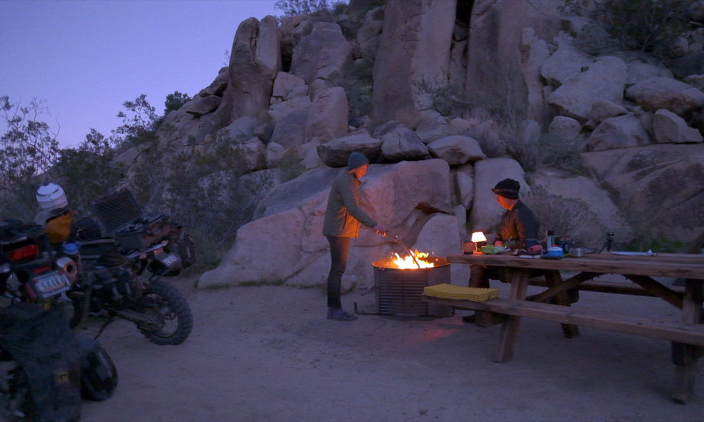 Two motorcyclists camping with a fire