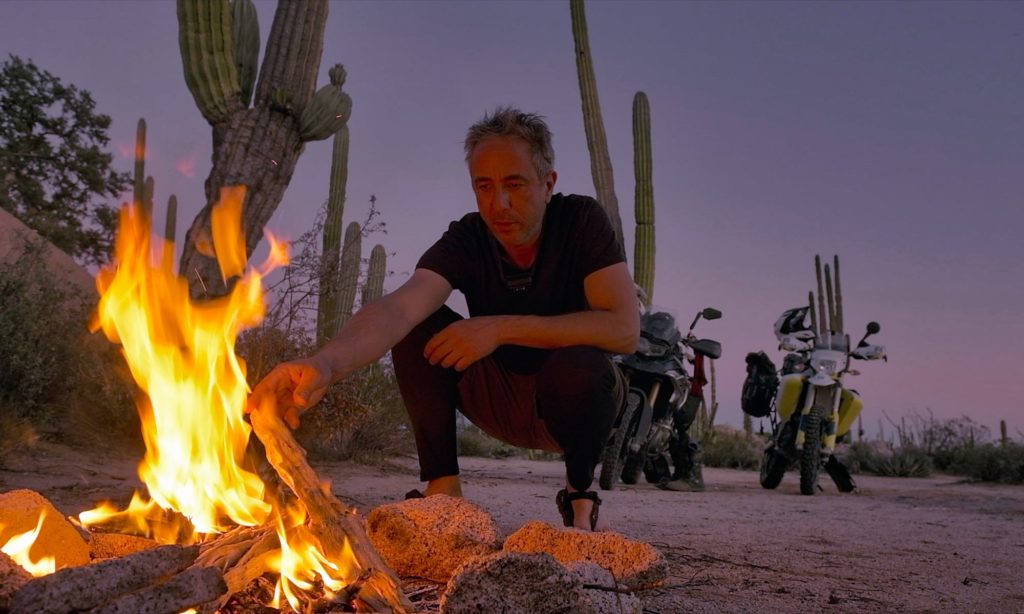 Sterling tending to campfire with motorcycles