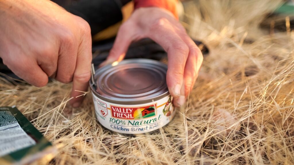 Opening can of chicken while motorcycle camping