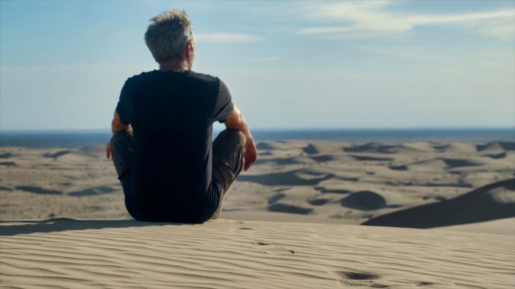 man looking over desert sand dunes