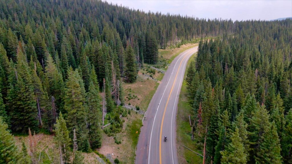 Sterling Noren riding motorcycle on paved road in Colorado mountains