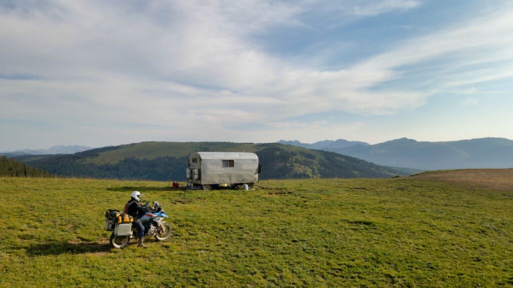 Sterling Noren on BMW motorcycle with sheepherder cabin on top of Ptarmigan Pass Colorado