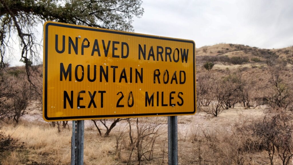 Unpaved narrow mountain road sign
