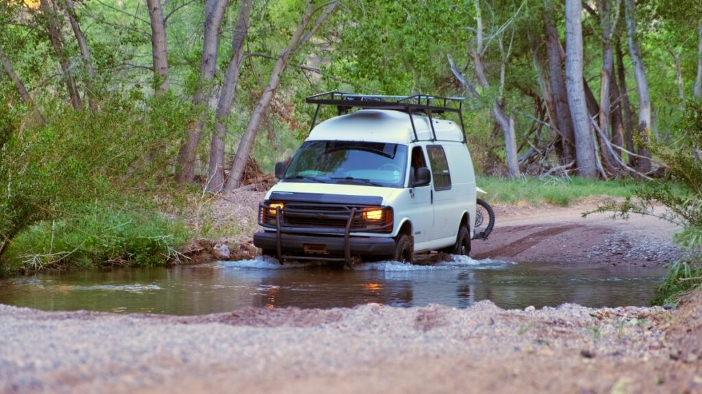 Chevrolet 4x4 van driving through creek