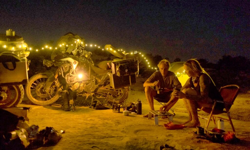 Sterling Noren and Eva Rupert motorcycle camping with string lights on Muley Point in Utah