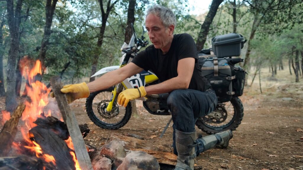 Sterling Noren building a campfire with his Husqvarna 701 motorcycle