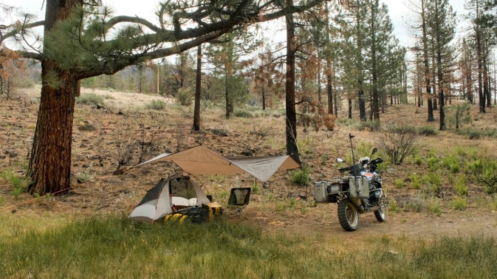 Sterling Noren with BMW motorcycle camping under a tarp