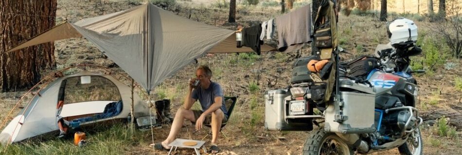 Sterling Noren with BMW motorcycle camping under a tarp