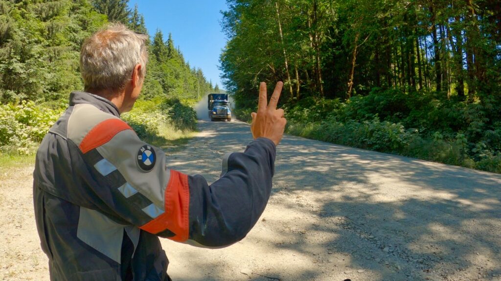 Motorcyclist waving at a passing logging truck